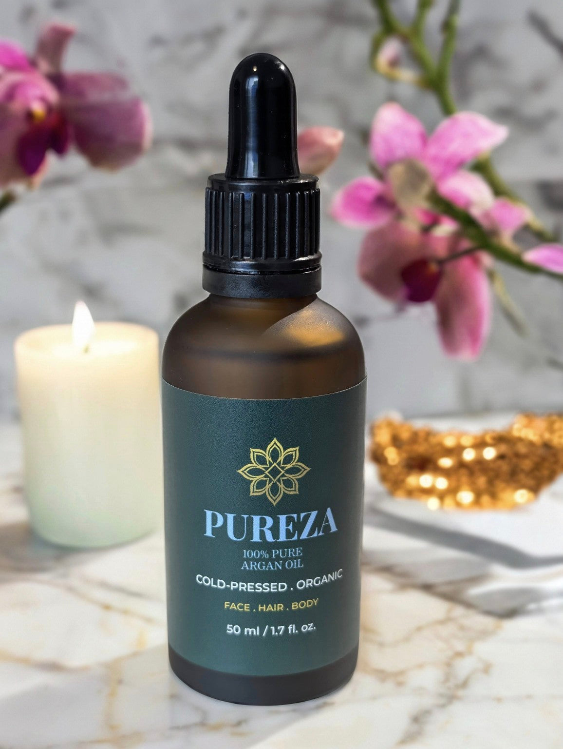 Bottle of Pureza argan oil with a decorative background featuring flowers and a candle.