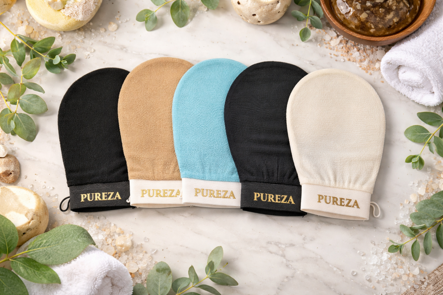 Five Pureza mittens in different colors on a textured surface with greenery.